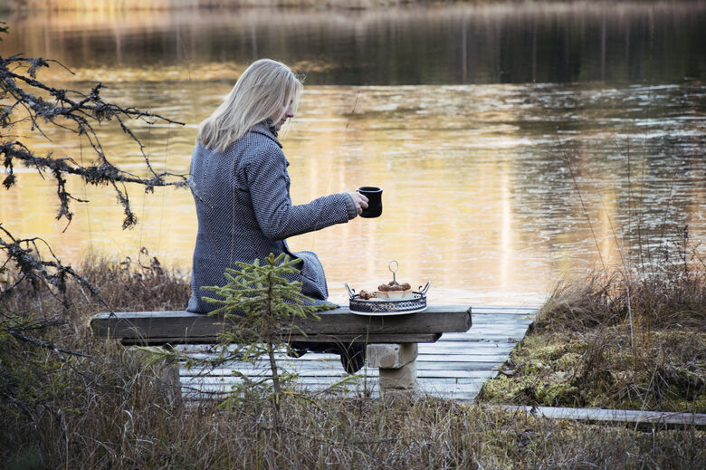 Evita Lūkina līdzgaitniecības sarunā dabā pie ezera ar tējas krūzi